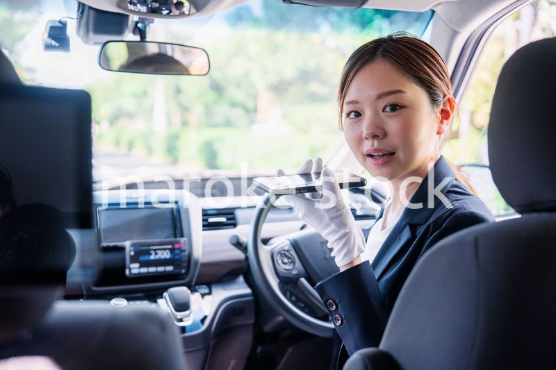 外国人への接客のために翻訳アプリを使う女性タクシードライバー