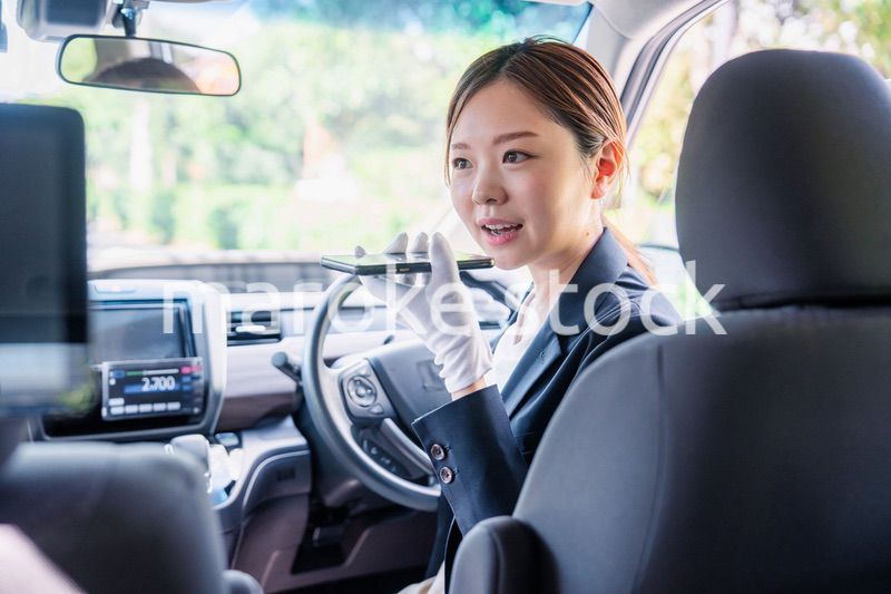 外国人への接客のために翻訳アプリを使う女性タクシードライバー