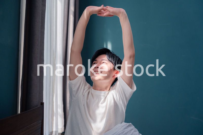 朝日が差し込む中で爽やかに目覚める若い男性