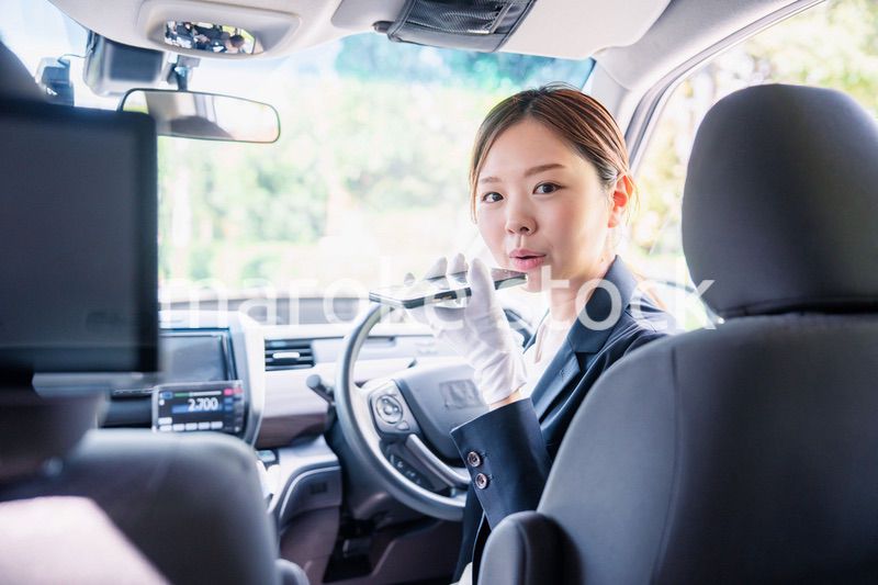 外国人への接客のために翻訳アプリを使う女性タクシードライバー