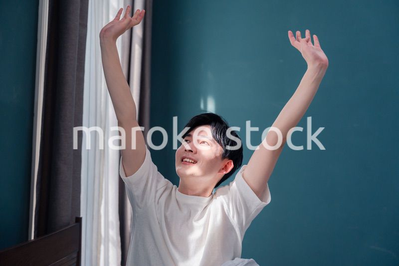 朝日が差し込む中で爽やかに目覚める若い男性