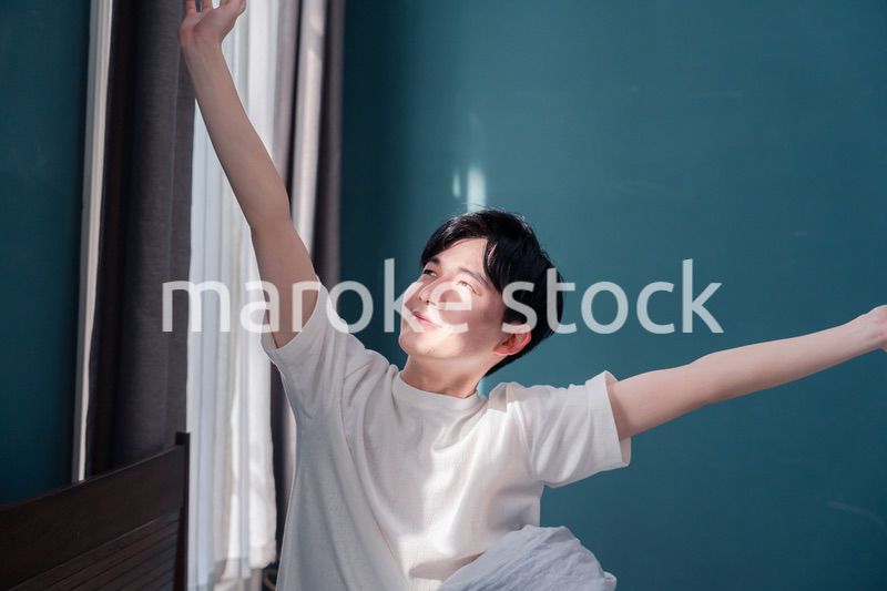 朝日が差し込む中で爽やかに目覚める若い男性