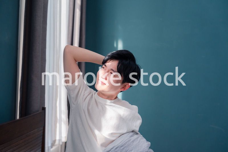 朝日が差し込む中で爽やかに目覚める若い男性