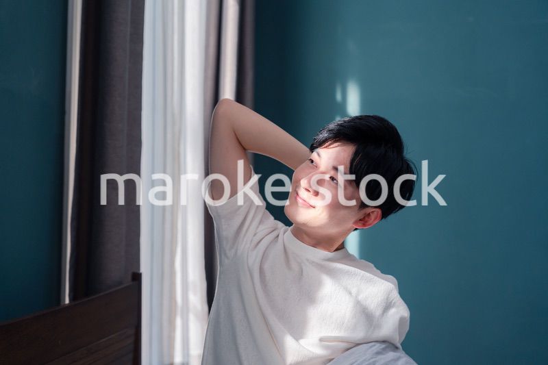 朝日が差し込む中で爽やかに目覚める若い男性