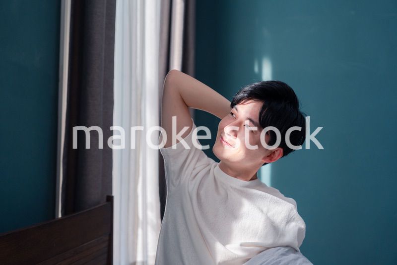 朝日が差し込む中で爽やかに目覚める若い男性