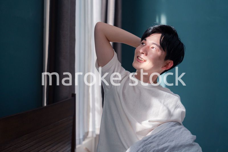 朝日が差し込む中で爽やかに目覚める若い男性