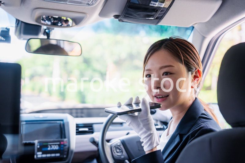 外国人への接客のために翻訳アプリを使う女性タクシードライバー