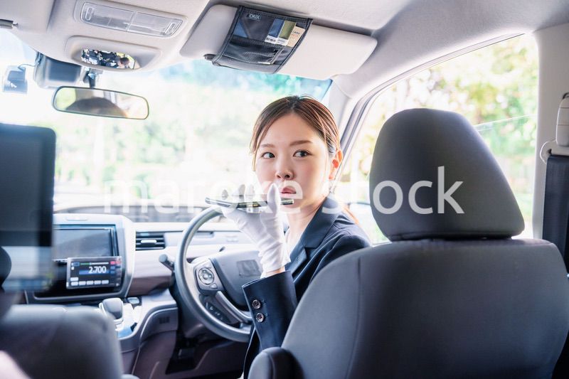 外国人への接客のために翻訳アプリを使う女性タクシードライバー
