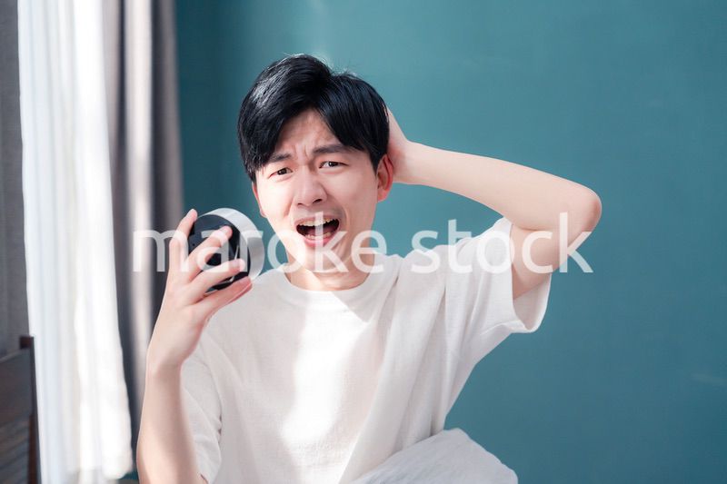 寝坊をして焦る若い男性