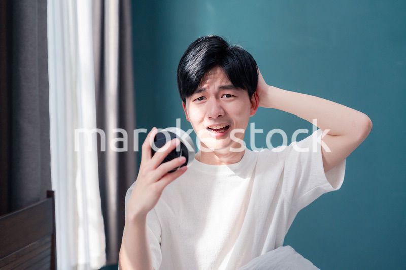 寝坊をして焦る若い男性