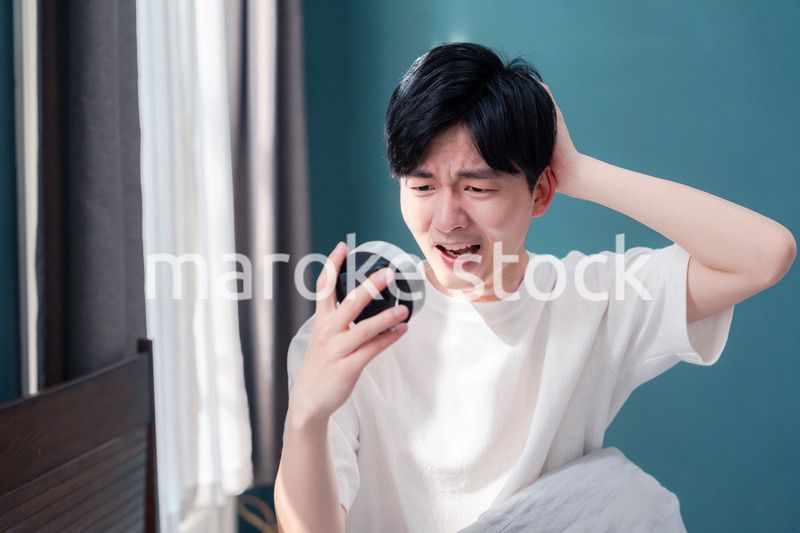 寝坊をして焦る若い男性