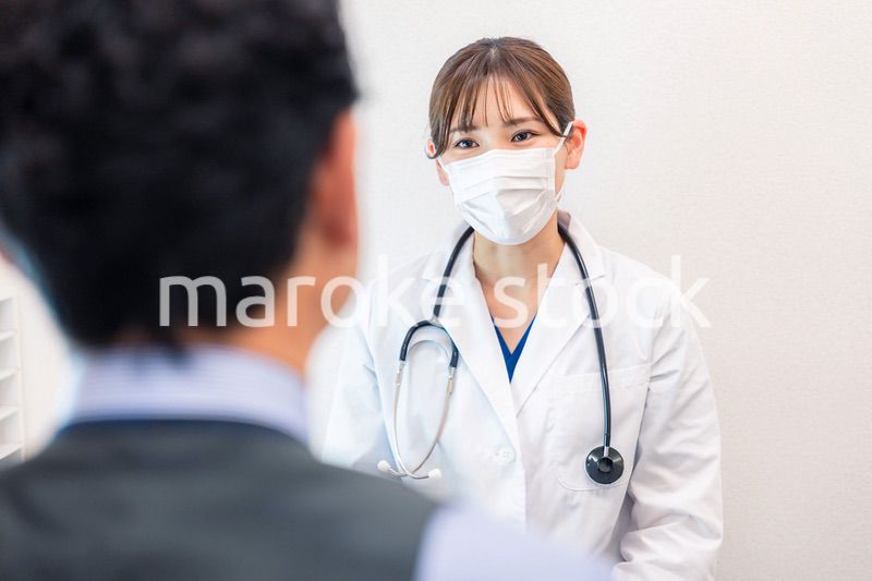 病院で男性患者の問診をする女性医師