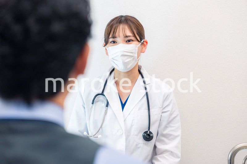 病院で男性患者の問診をする女性医師