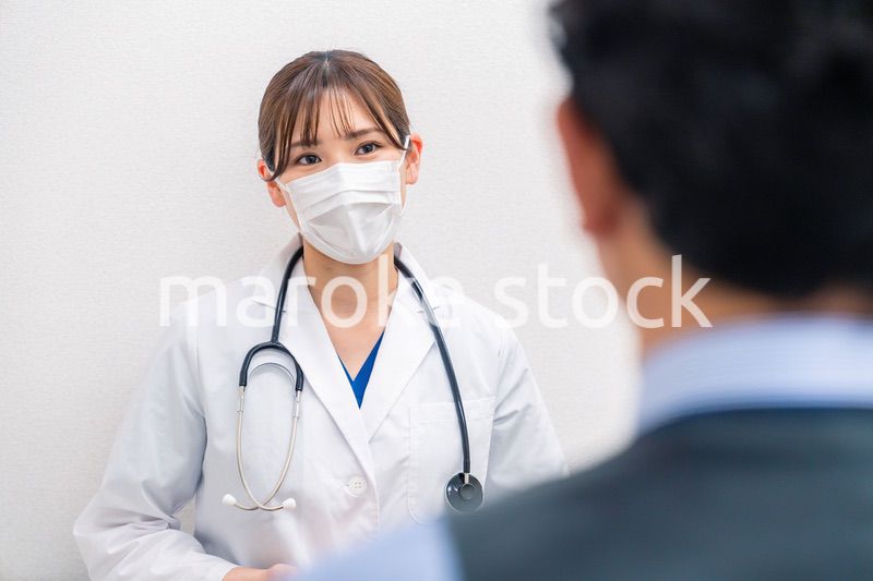 病院で男性患者の問診をする女性医師