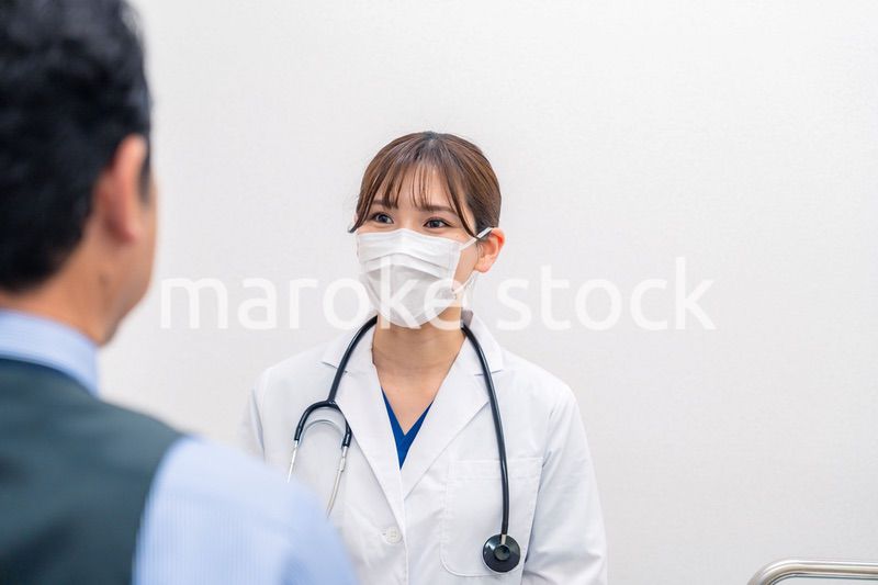 病院で男性患者の問診をする女性医師