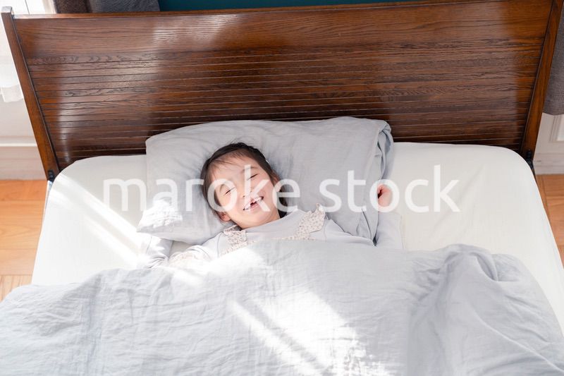 ベッドでぐっすりと寝る小さな女の子