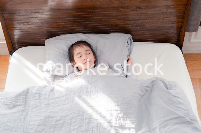 ベッドでぐっすりと寝る小さな女の子