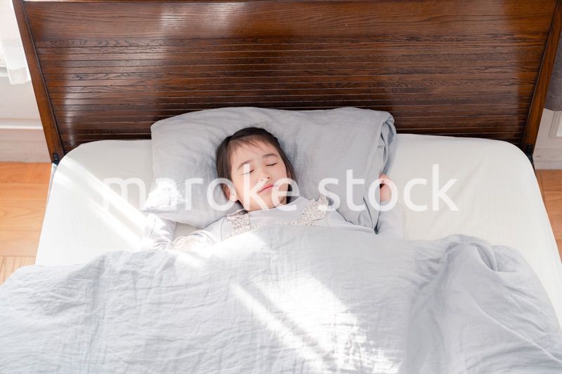 ベッドでぐっすりと寝る小さな女の子
