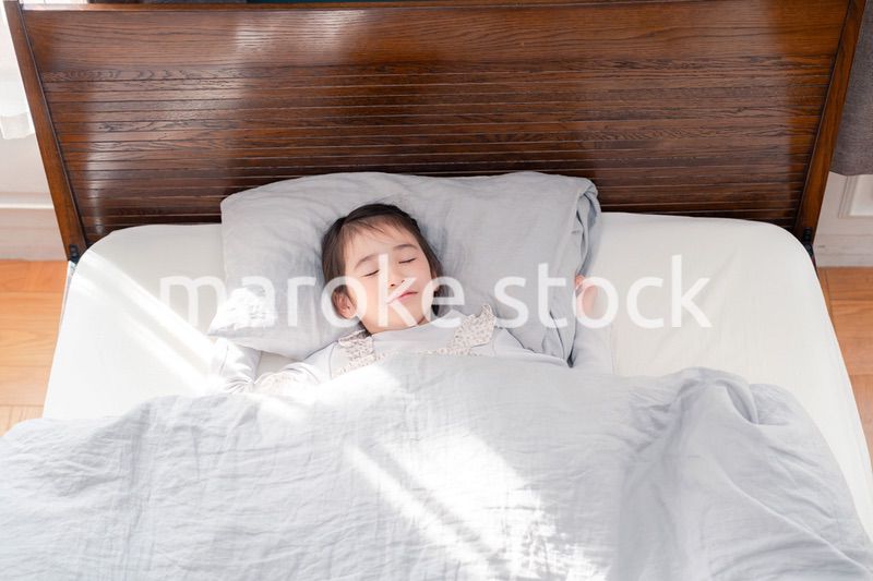 ベッドでぐっすりと寝る小さな女の子
