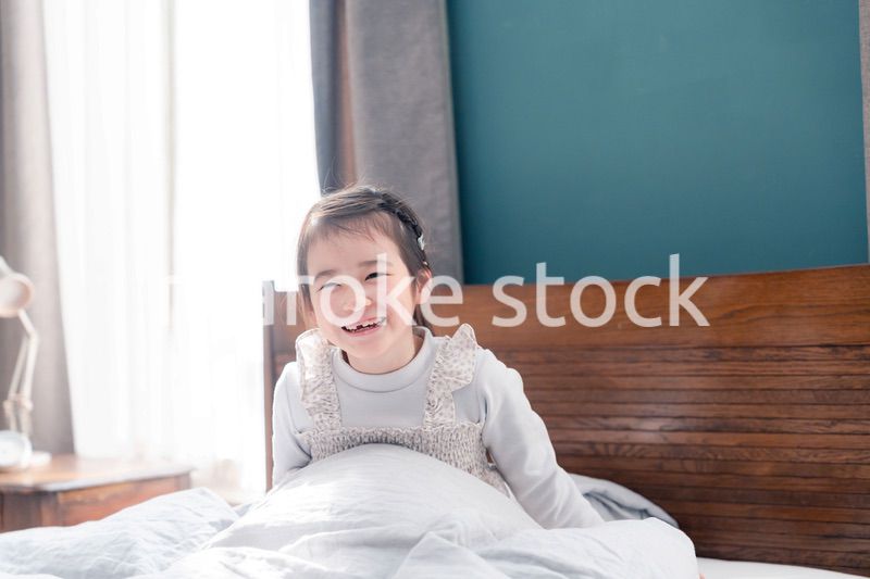 朝ベッドで目覚めて伸びをする小さな女の子