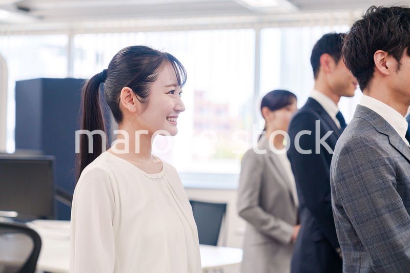 朝会で笑顔で話を聞くオフィスワーカー