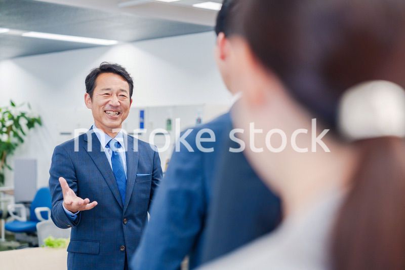 オフィスでの朝礼で挨拶をする管理職の男性