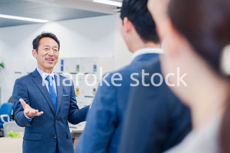 オフィスでの朝礼で挨拶をする管理職の男性