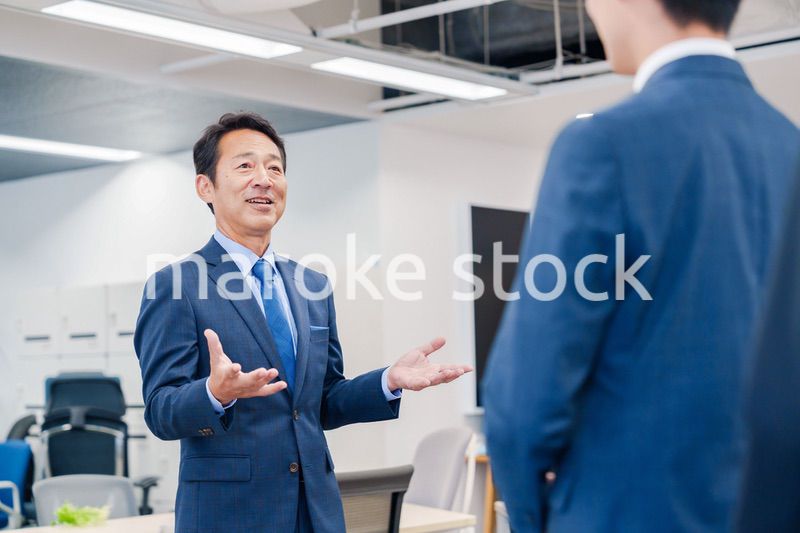 オフィスでの朝礼で挨拶をする管理職の男性