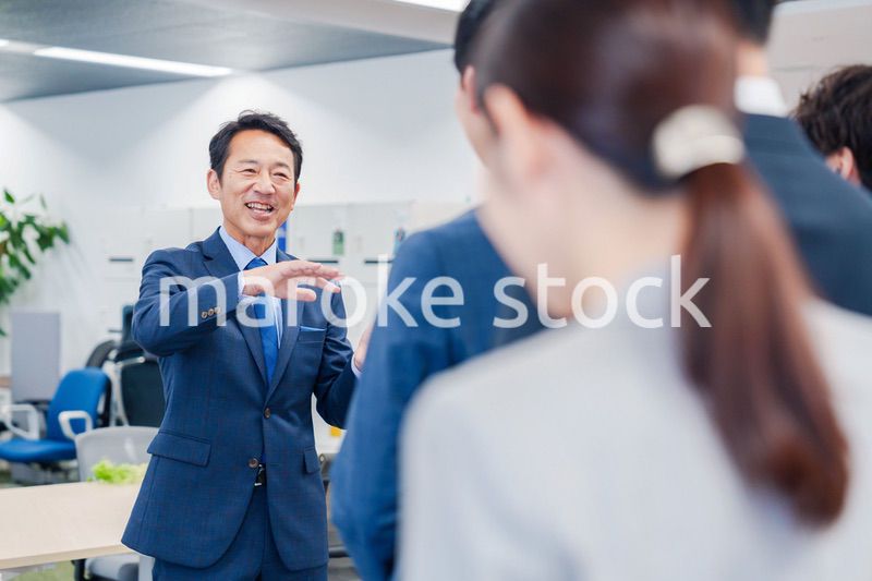 オフィスでの朝礼で挨拶をする管理職の男性