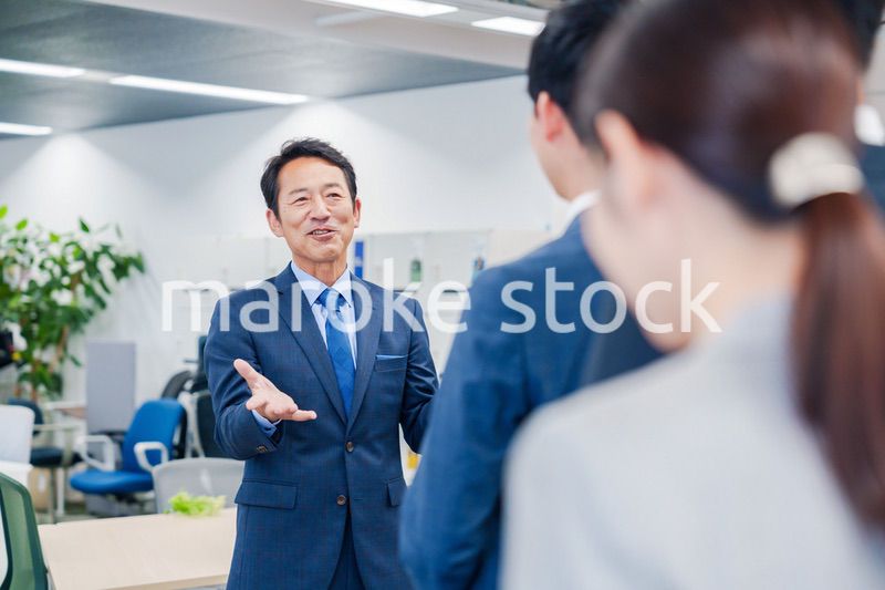オフィスでの朝礼で挨拶をする管理職の男性