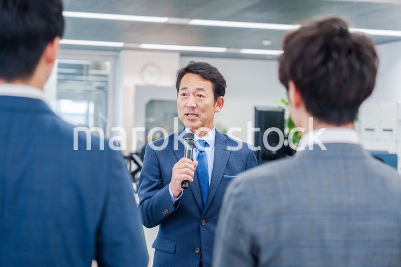 オフィスでの朝礼で挨拶をする管理職の男性