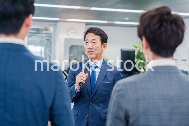 オフィスでの朝礼で挨拶をする管理職の男性