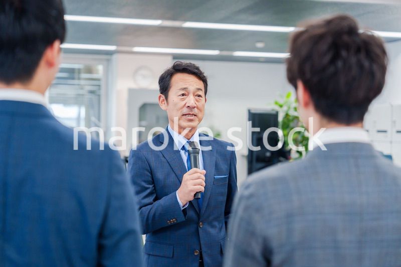 オフィスでの朝礼で挨拶をする管理職の男性