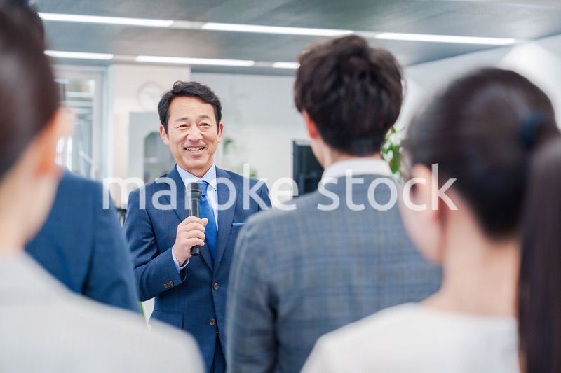 オフィスでの朝礼で挨拶をする管理職の男性