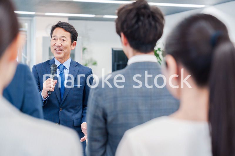 オフィスでの朝礼で挨拶をする管理職の男性