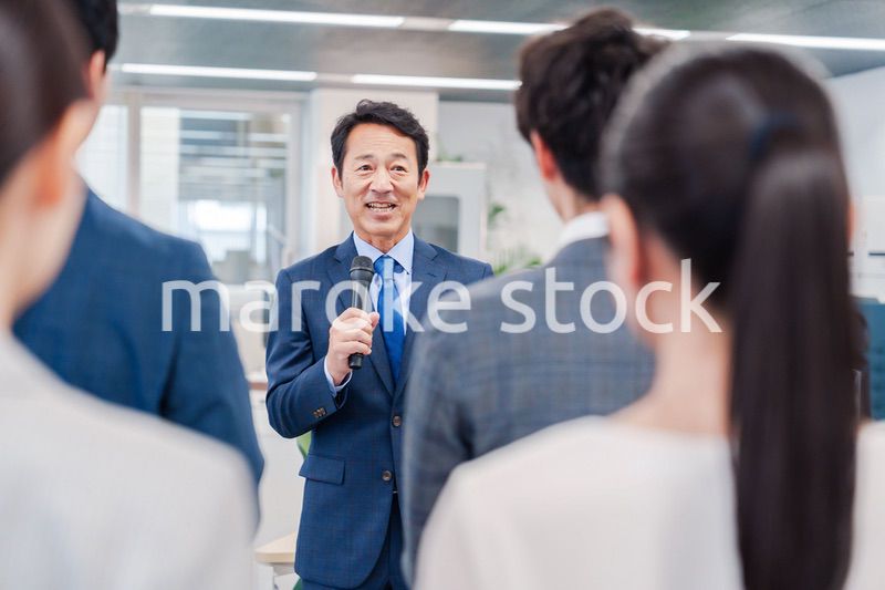 オフィスでの朝礼で挨拶をする管理職の男性