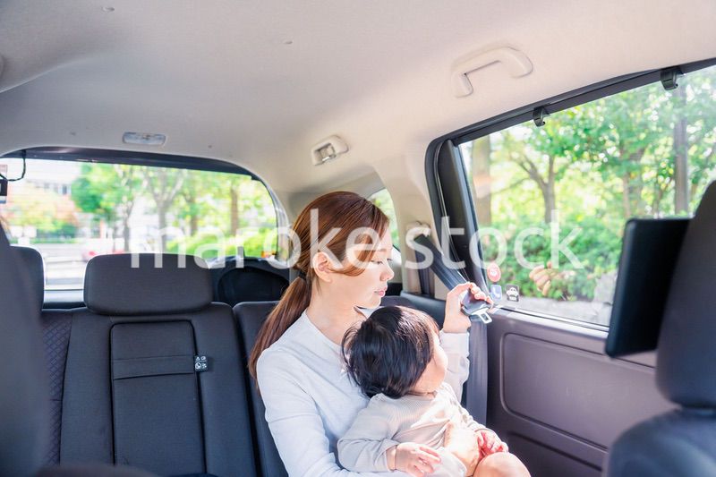 タクシーでシートベルトをする子連れのお母さん