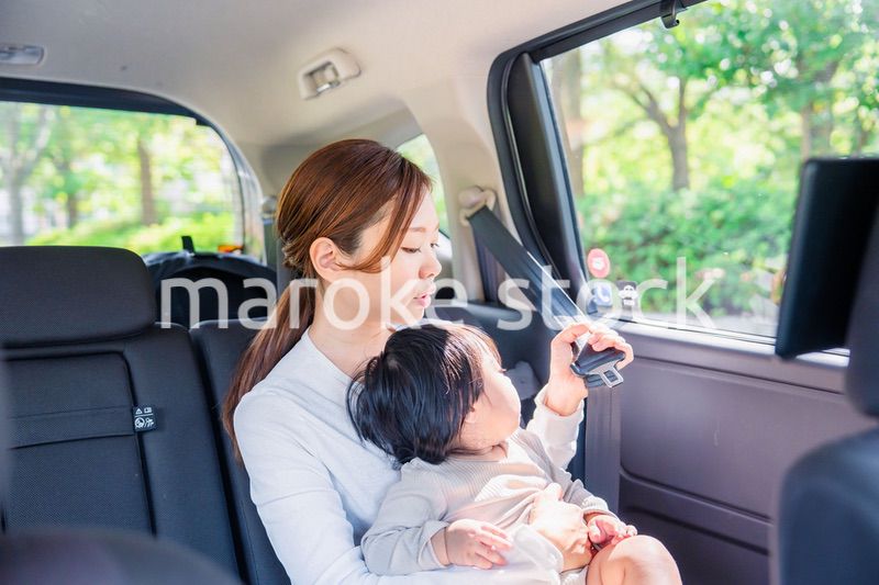 タクシーでシートベルトをする子連れのお母さん