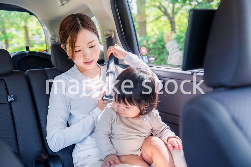 タクシーでシートベルトをする子連れのお母さん