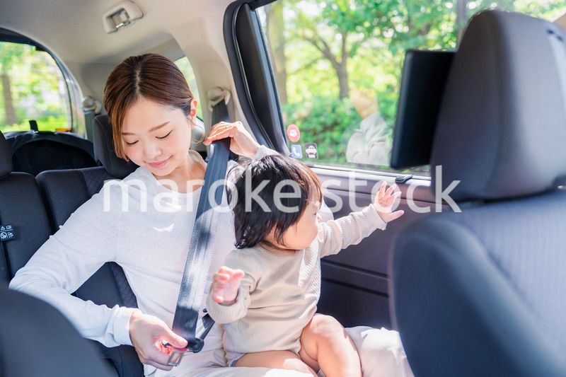 タクシーでシートベルトをする子連れのお母さん