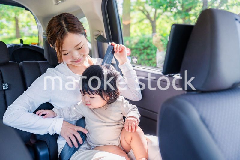 タクシーでシートベルトをする子連れのお母さん