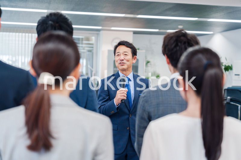 オフィスでの朝礼で挨拶をする管理職の男性