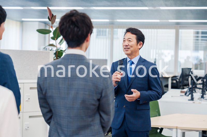 オフィスでの朝礼で挨拶をする管理職の男性