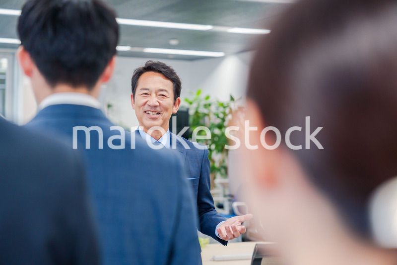 オフィスでの朝礼で挨拶をする管理職の男性