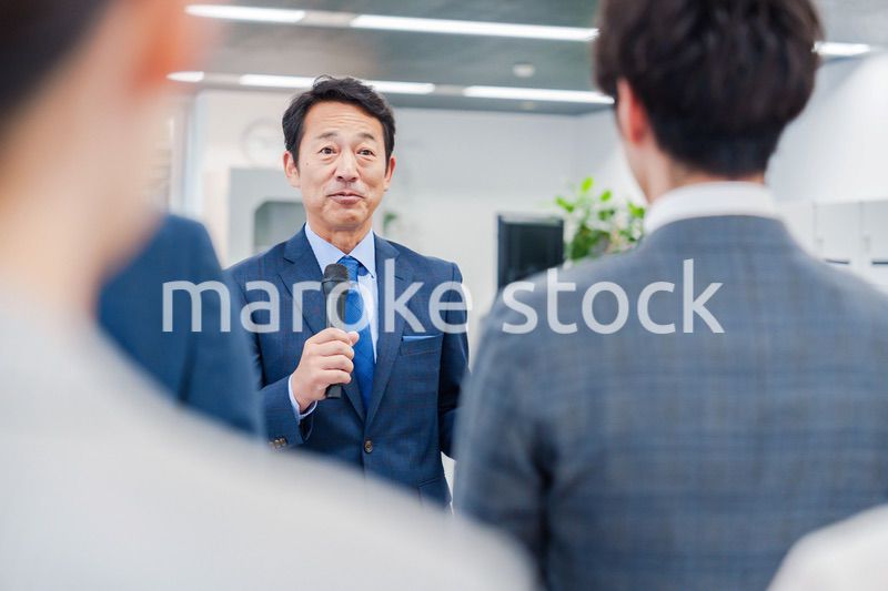 オフィスでの朝礼で挨拶をする管理職の男性