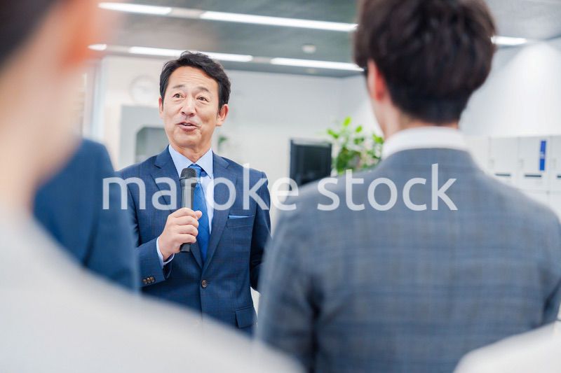オフィスでの朝礼で挨拶をする管理職の男性