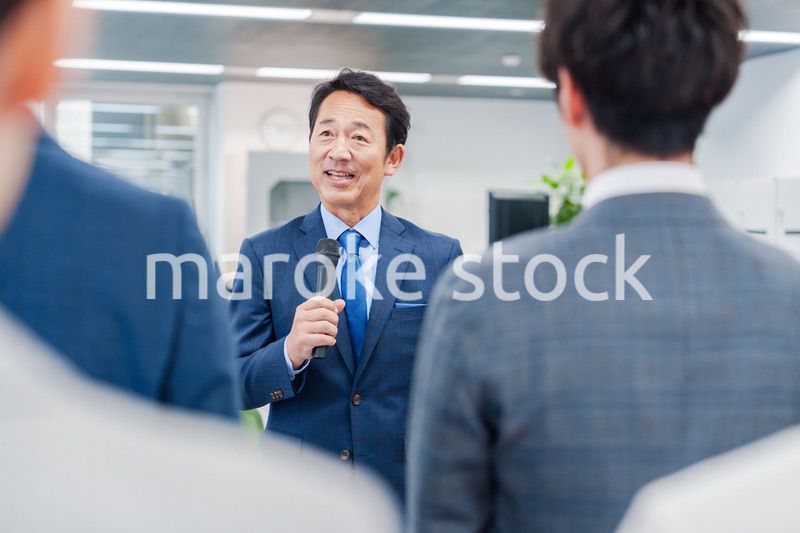 オフィスでの朝礼で挨拶をする管理職の男性