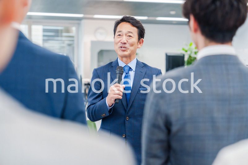 オフィスでの朝礼で挨拶をする管理職の男性