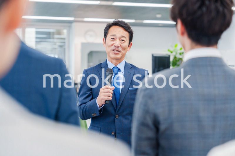 オフィスでの朝礼で挨拶をする管理職の男性