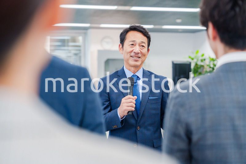 オフィスでの朝礼で挨拶をする管理職の男性